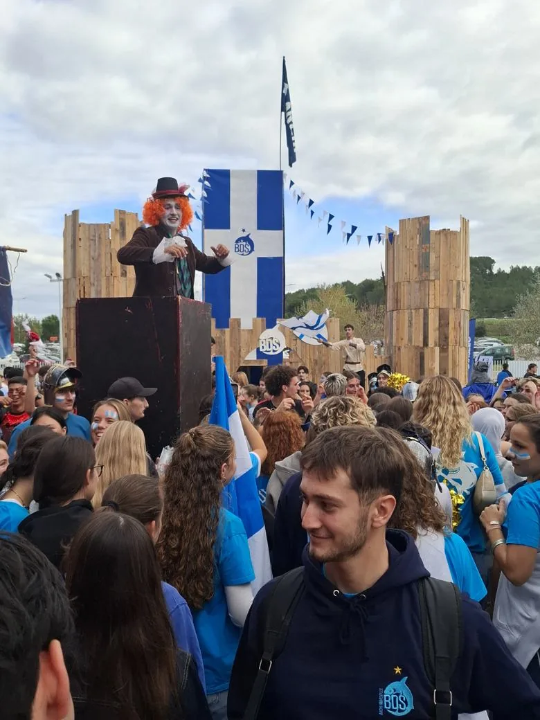 Stand Archi BDS : château médiéval en palettes de bois, drapeau bleu et blanc BDS, meneur sur podium